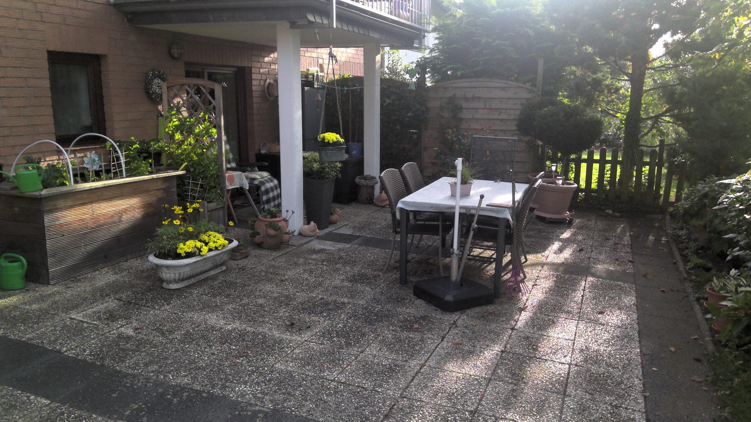 Und nochmal die Erdgeschoss-Terrasse, diesmal von der anderen Seite. Eine neue Windschutzwand sowie ein Törchen als Durchgang zur Rasenfläche werden die mit Efeu bewachsene Wand und den kleinen Zaun rechts davon ersetzen. Ohne die großen Gewächse hinter dem Zaun wird es auch wieder heller im Erdgeschoss und auf der Terrasse.
